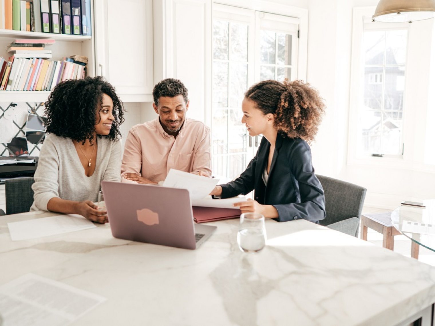 Couple talking to a real estate agent at a kitchen island.