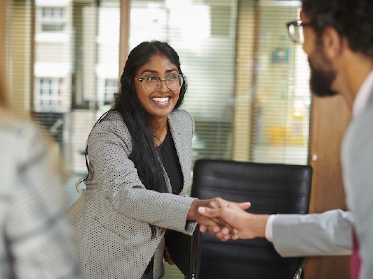 Man and woman shake hands at a job interview.