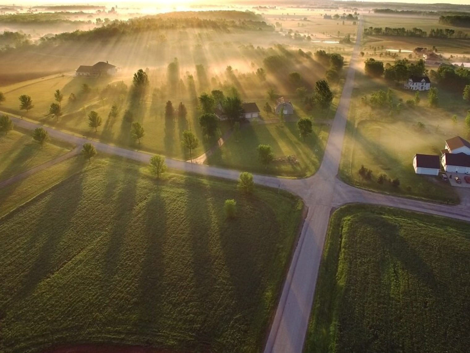 Aerial view of farm properties with a radiant sunrise.