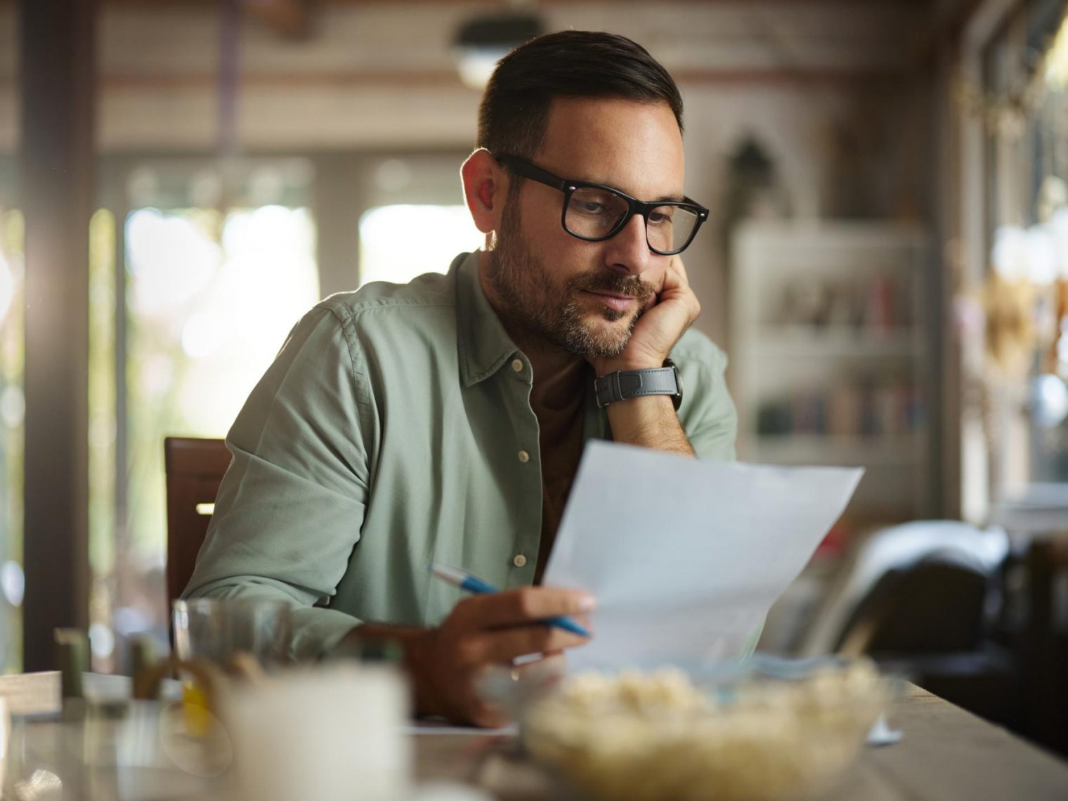 A man sitting at a table looking at his statement of service document.