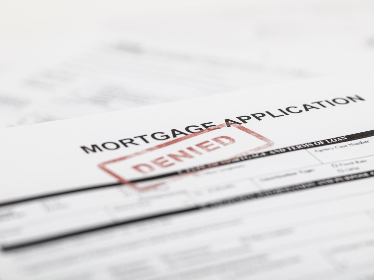 A paper mortgage application with "denied" stamped across it.