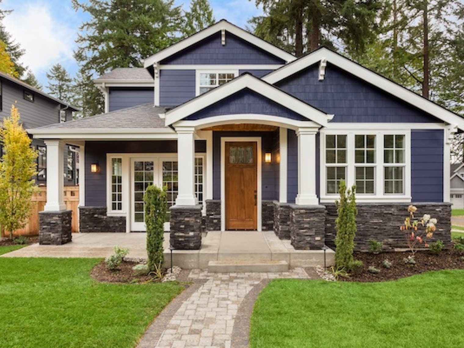 Exterior of a nice house with blue vinyl and a wood door.